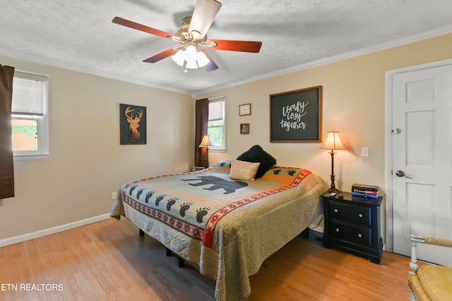 bedroom with ceiling fan, ornamental molding, a textured ceiling, and hardwood / wood-style flooring