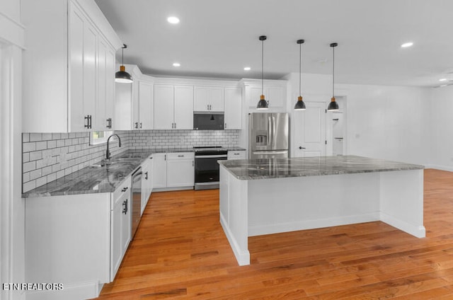 kitchen with appliances with stainless steel finishes, light hardwood / wood-style floors, white cabinetry, pendant lighting, and a center island