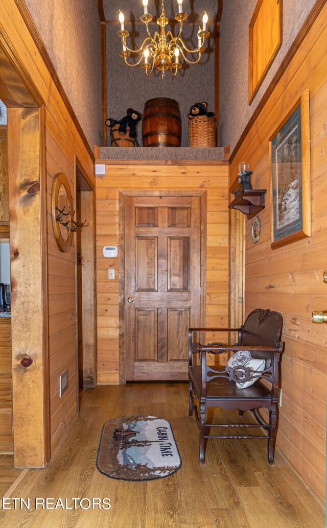 entrance foyer with hardwood / wood-style floors, an inviting chandelier, and wooden walls