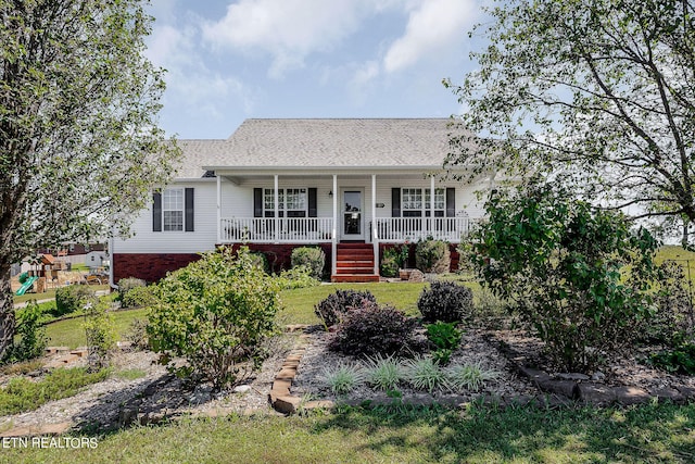 ranch-style house featuring covered porch and a front yard