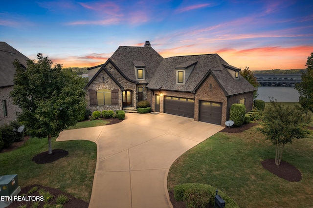 french country style house featuring a garage and a lawn