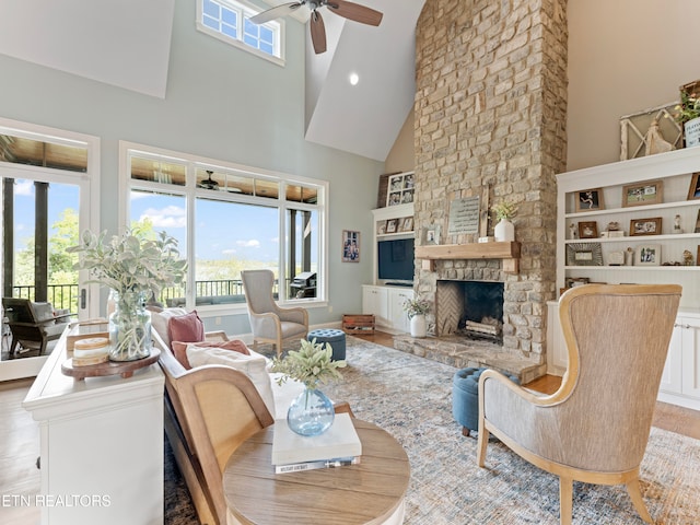 living room with high vaulted ceiling, ceiling fan, a fireplace, and light hardwood / wood-style flooring