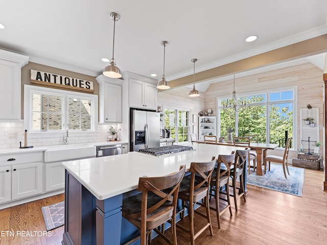 kitchen with stainless steel appliances, decorative light fixtures, a center island, a breakfast bar, and vaulted ceiling