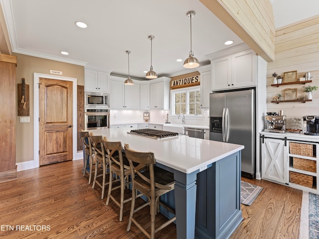 kitchen featuring a kitchen breakfast bar, a center island, stainless steel appliances, hardwood / wood-style flooring, and white cabinets