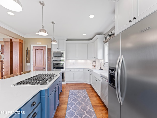 kitchen featuring blue cabinetry, crown molding, white cabinetry, built in appliances, and light hardwood / wood-style floors