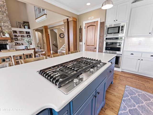 kitchen with white cabinets, appliances with stainless steel finishes, light hardwood / wood-style flooring, and decorative columns