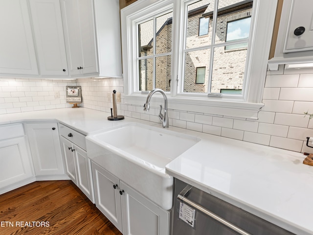 kitchen featuring sink, decorative backsplash, dark wood-type flooring, stainless steel dishwasher, and white cabinets