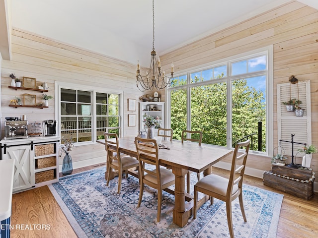 dining room featuring light hardwood / wood-style flooring, a notable chandelier, and wooden walls