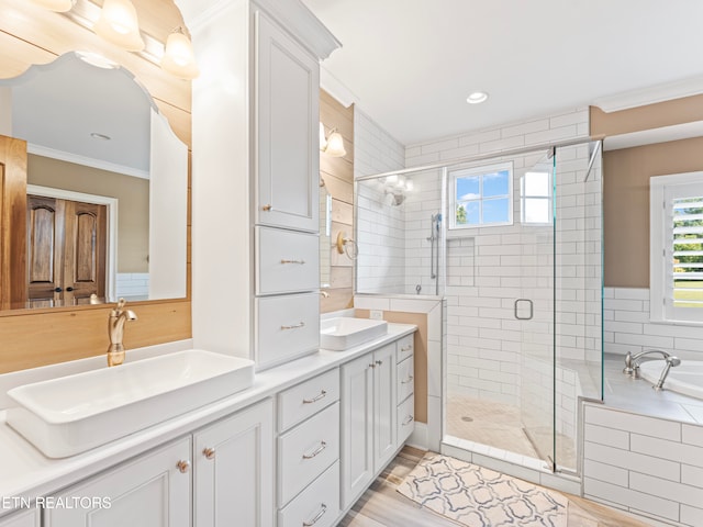 bathroom featuring wood-type flooring, shower with separate bathtub, ornamental molding, and vanity