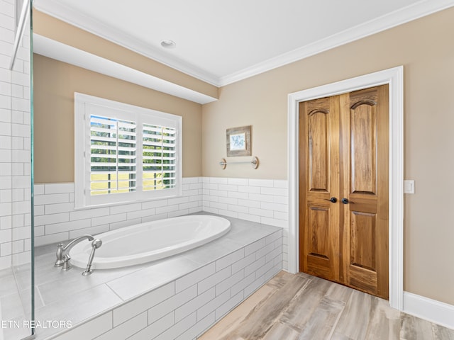 bathroom featuring tiled tub, ornamental molding, and hardwood / wood-style floors