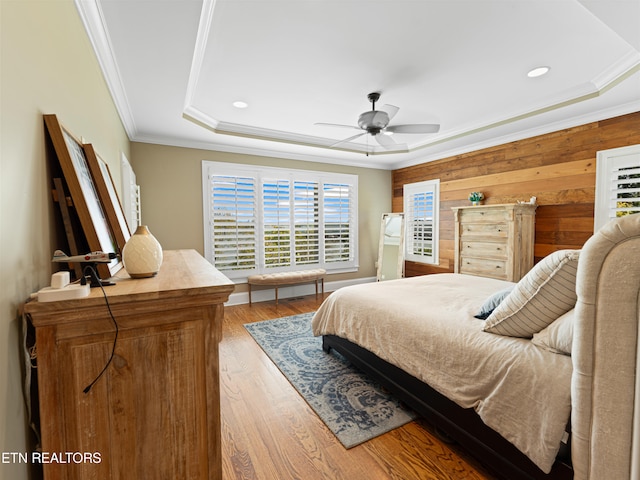 bedroom featuring crown molding, ceiling fan, wooden walls, and light hardwood / wood-style floors