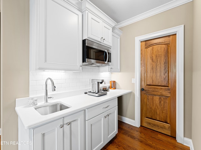 kitchen with crown molding, dark hardwood / wood-style flooring, sink, and white cabinets