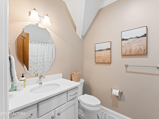 bathroom with vanity, toilet, and lofted ceiling