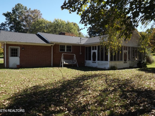 back of house featuring a lawn and a sunroom