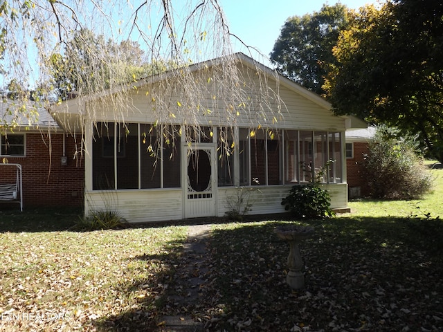 rear view of property with a lawn and a sunroom