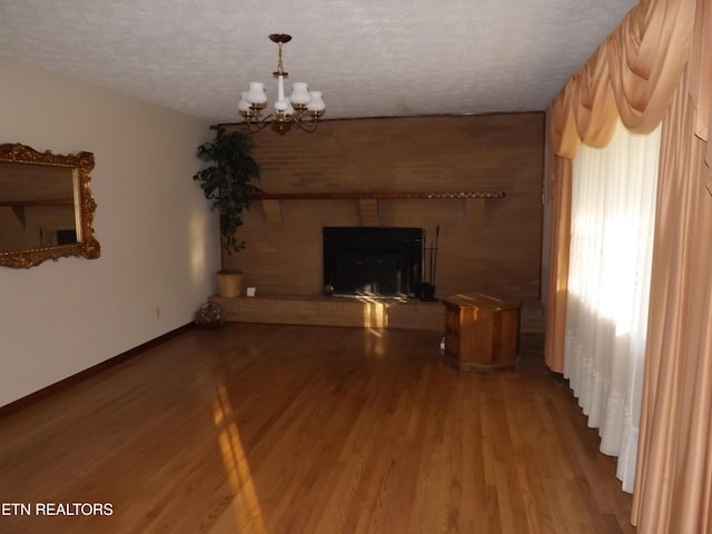 unfurnished living room featuring hardwood / wood-style floors, a textured ceiling, and an inviting chandelier