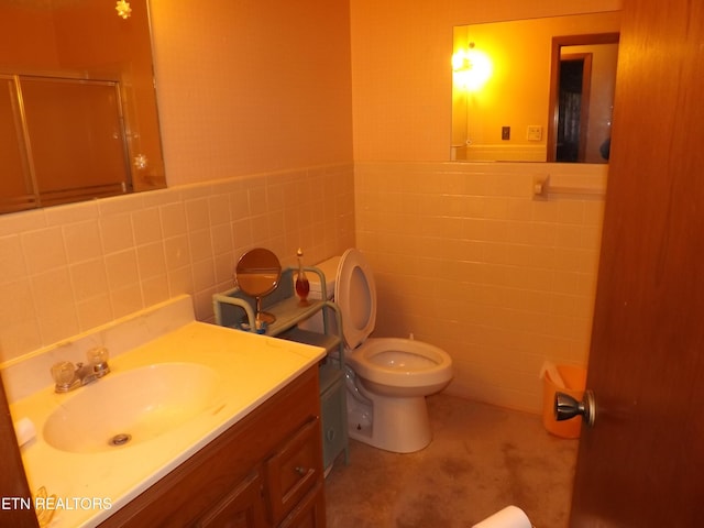 bathroom with vanity, toilet, an enclosed shower, and tile walls