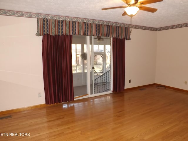 empty room featuring hardwood / wood-style floors, ceiling fan, and a textured ceiling