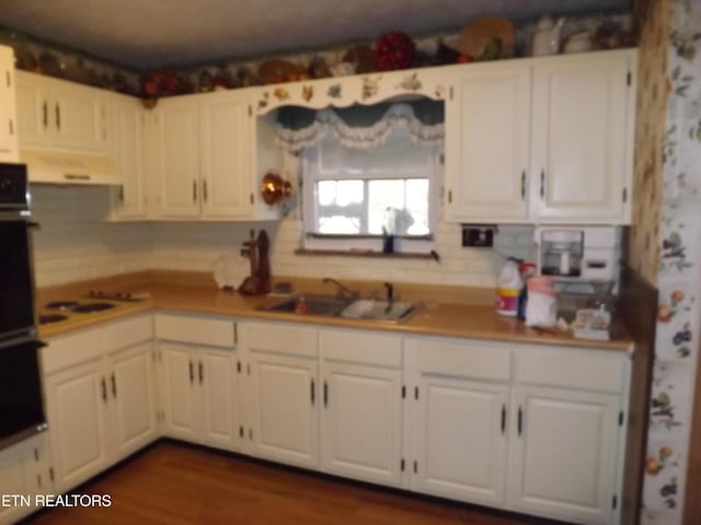 kitchen featuring white stovetop, dark hardwood / wood-style flooring, white cabinetry, and sink