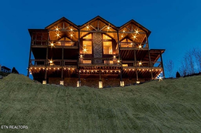 view of front of house featuring a balcony and a lawn