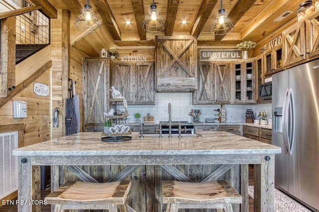 kitchen featuring hanging light fixtures, a center island, stainless steel fridge, decorative backsplash, and a breakfast bar