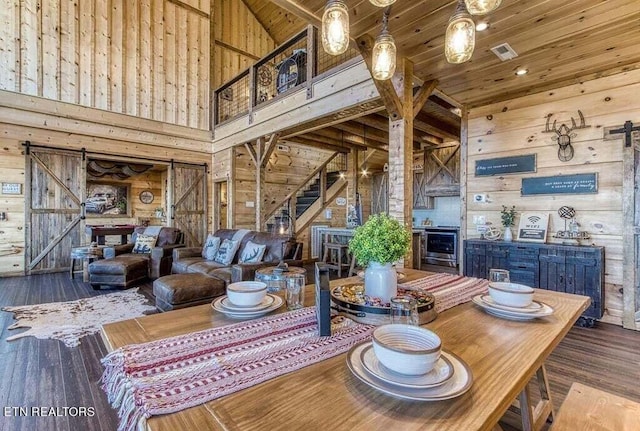 interior space featuring a barn door, wood walls, wood-type flooring, and high vaulted ceiling