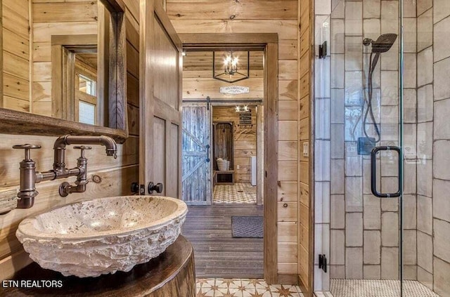 bathroom featuring a shower with door, vanity, and wood walls