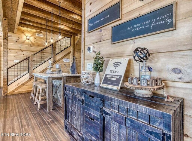 bar featuring dark wood-type flooring, wooden walls, and beam ceiling