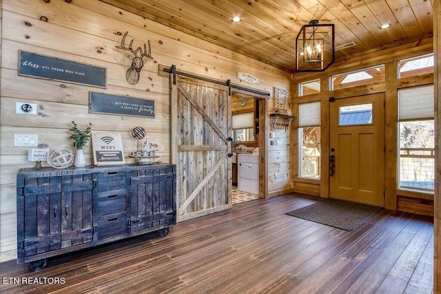 foyer entrance featuring a barn door, wood walls, wood ceiling, and dark hardwood / wood-style floors