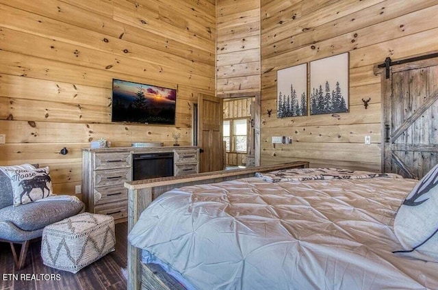 bedroom with a barn door, hardwood / wood-style floors, and wooden walls