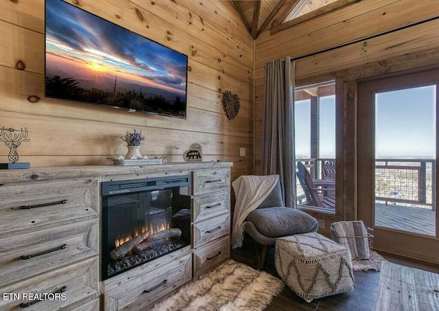 living area with vaulted ceiling, a healthy amount of sunlight, hardwood / wood-style floors, and wood walls