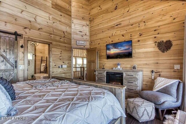 bedroom featuring a barn door, wood walls, and a towering ceiling