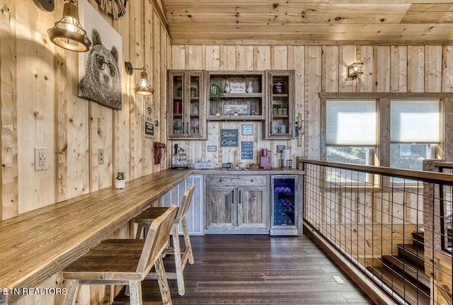 bar with wooden ceiling, dark hardwood / wood-style flooring, beverage cooler, and wooden walls