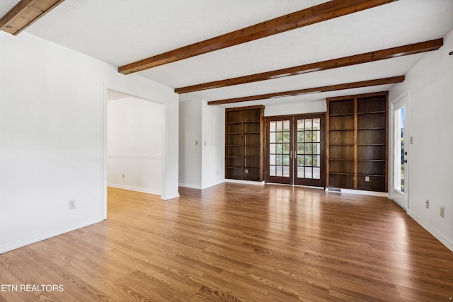 unfurnished living room featuring a textured ceiling, light hardwood / wood-style flooring, beamed ceiling, and french doors