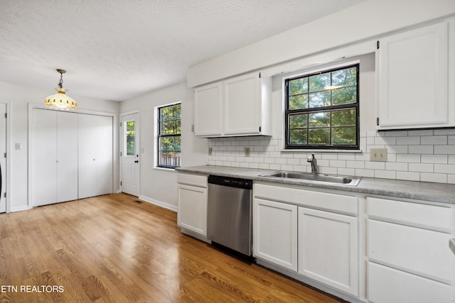 kitchen featuring stainless steel dishwasher, a healthy amount of sunlight, sink, and white cabinets