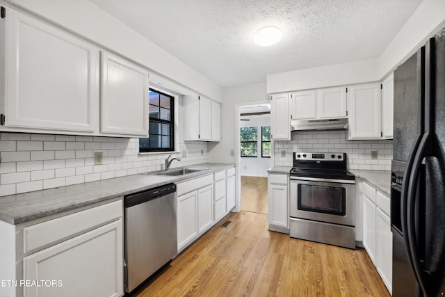 kitchen featuring appliances with stainless steel finishes, white cabinetry, sink, and light hardwood / wood-style floors