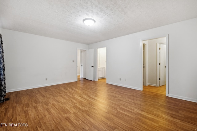 unfurnished room with a textured ceiling and light hardwood / wood-style flooring