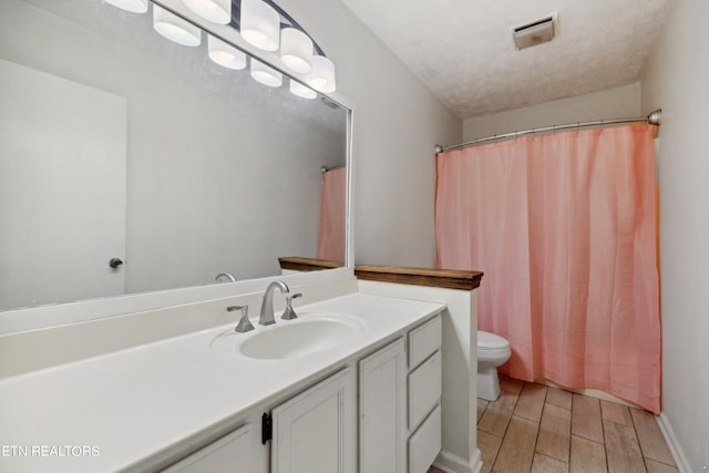 bathroom featuring a textured ceiling, vanity, toilet, and wood-type flooring