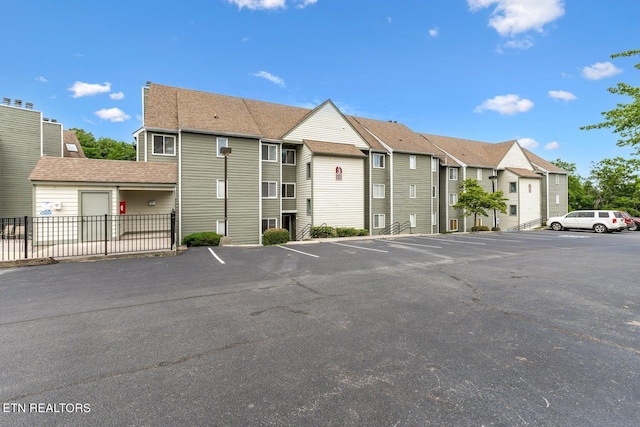 view of building exterior featuring a residential view, fence, and uncovered parking