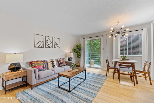 living room featuring a textured ceiling, an inviting chandelier, and light hardwood / wood-style flooring