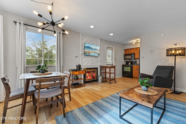 living room featuring light hardwood / wood-style flooring, a high end fireplace, a chandelier, and plenty of natural light