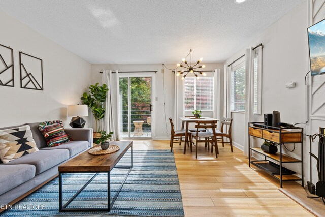 living room with light wood-type flooring, a textured ceiling, and a chandelier