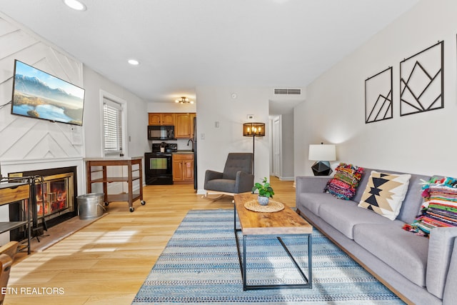 living room featuring light wood-type flooring and a fireplace