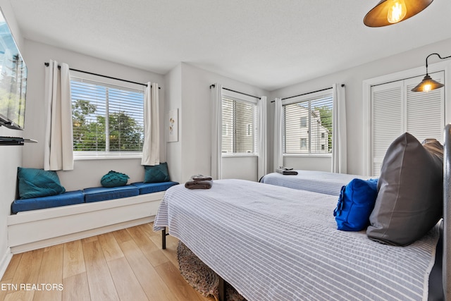 bedroom with wood-type flooring, a textured ceiling, and multiple windows