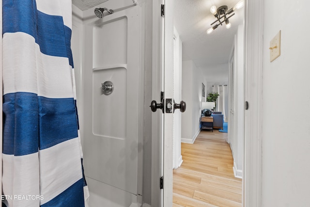 bathroom with a textured ceiling, a shower, and hardwood / wood-style flooring