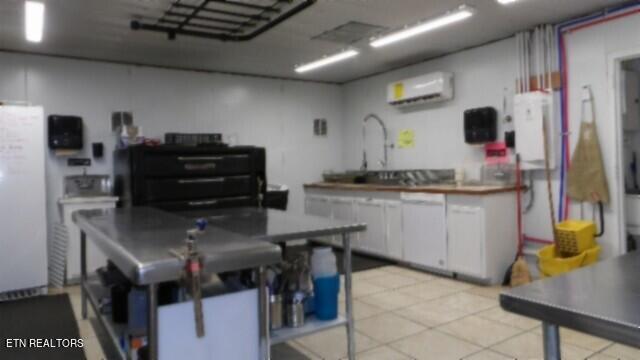 kitchen featuring a wall mounted AC, white fridge, and white cabinetry