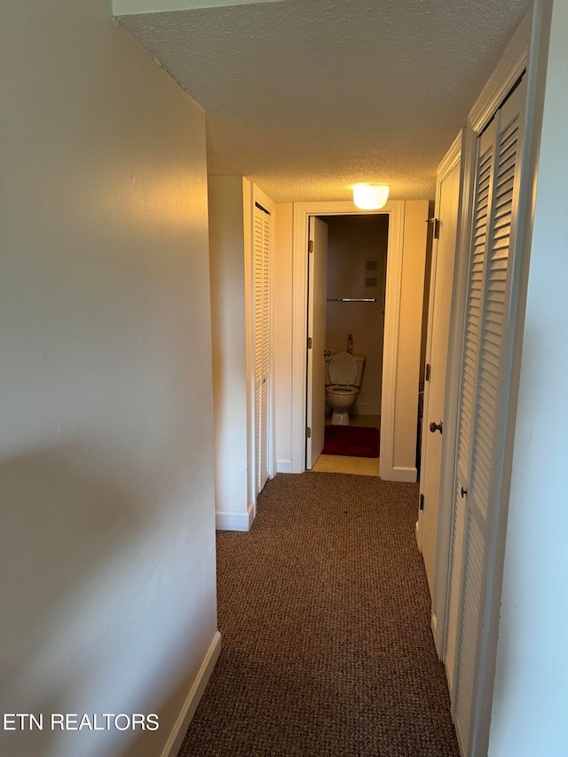 corridor featuring carpet flooring and a textured ceiling