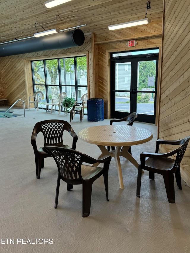 dining area with wooden ceiling, a wealth of natural light, wooden walls, and carpet floors