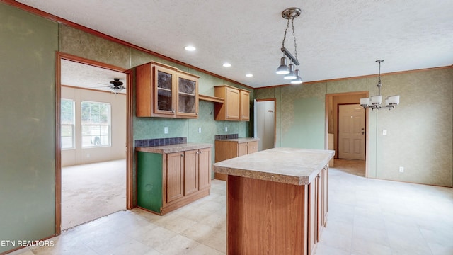 kitchen with a center island, ornamental molding, ceiling fan with notable chandelier, and hanging light fixtures