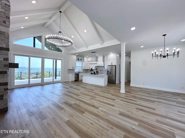 unfurnished living room with a chandelier, light wood-type flooring, and high vaulted ceiling